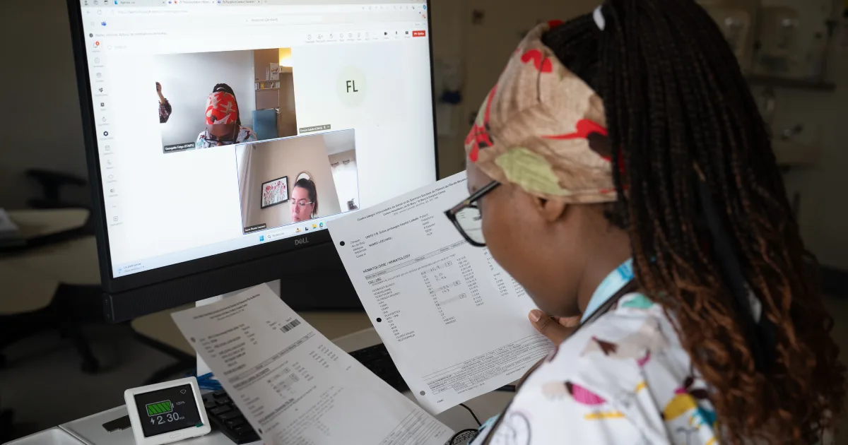 Infirmière devant un écran en rencontre virtuelle avec des collègues.